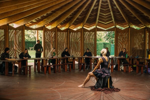 a life drawing class in serpentine pavillion sat in a circle around a model in fashionable dress