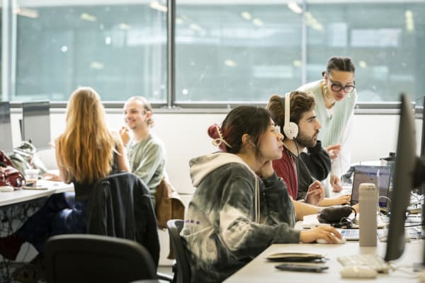 A group of students studying and talking together in front of computers.