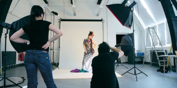 Photography studio with female model in a dress and two photographers