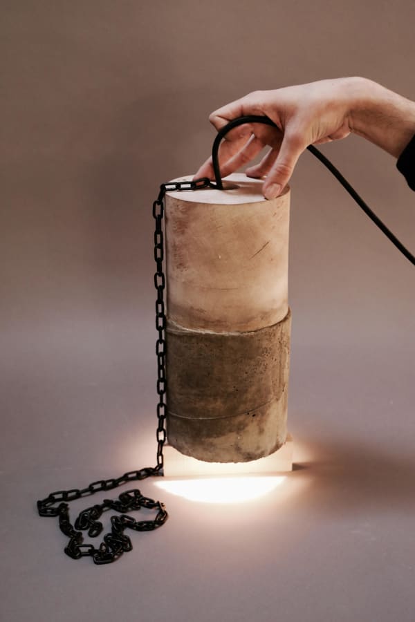 a cylindrical weight with an iron chain attached. Illuminated by a low light lamp at the base of the object. 