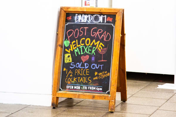 Sandwich board sign with colourful chalk text stating postgrad mixer sold out