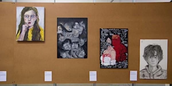 A variety of work from UAL Awarding Body's Origins Creatives 2022 exhibition hung up on a wall