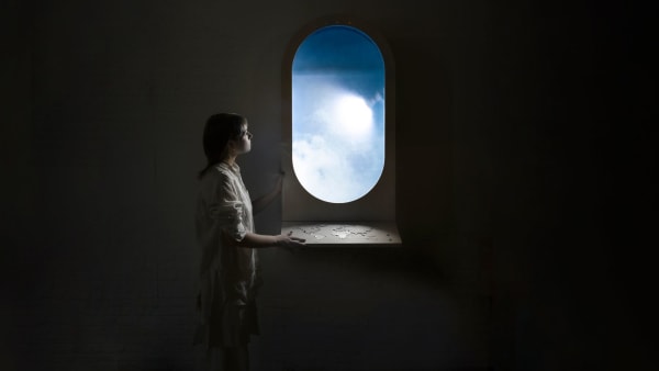 A person looking out of an aeroplane window with a map of the world positioned underneath 