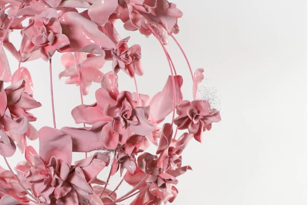 A globe shaped pink sculpture with sculpted flowers blooming out of it