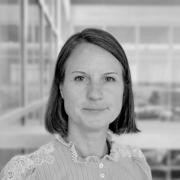 Jana Riedel, XR Project Manager, standing in front of a wall and smiling at the camera. The photo is in black and white. 