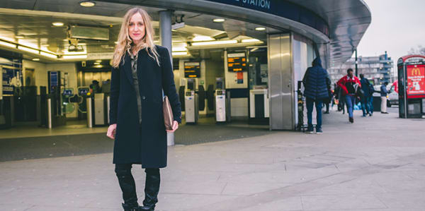 A portrait of a woman standing in front of a train station.
