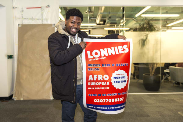Photograph of a man holding a shop poster.