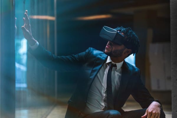 Image shows a man in a suit wearing a VR headset.