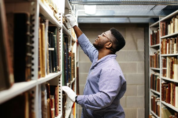 Black man researching in archives wearing white gloves