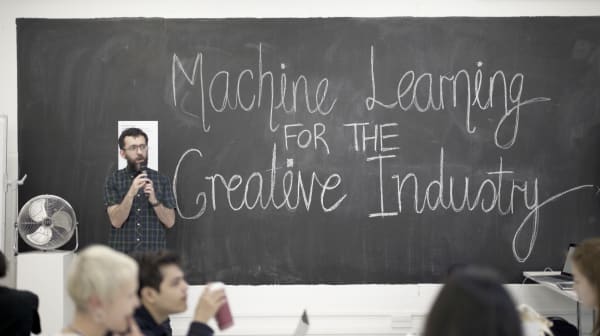 Man standing in front of chalk board with Machine Learning for the Creative Industry written in big letters