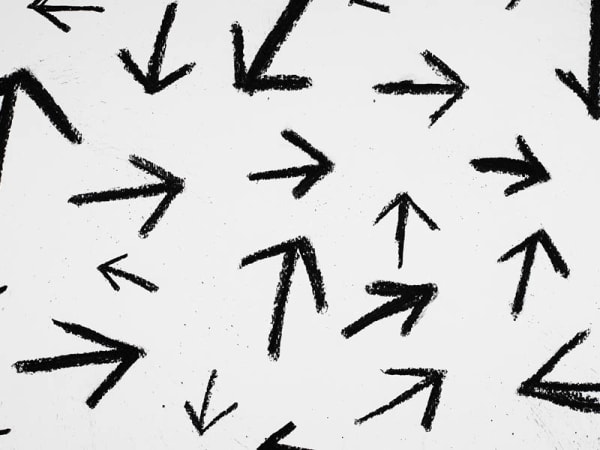 Multiple hand-drawn black arrows pointing in different directions, on a grey background.