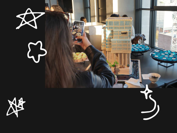 Student taking photo of a cake in the shape of LCF building on mobile phone