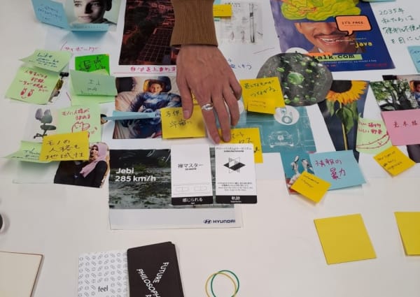 Future Philosophical Pills in use in a workshop in Tokyo. A table is spread with lots of media cuttings, post-its, images and other visual materials.