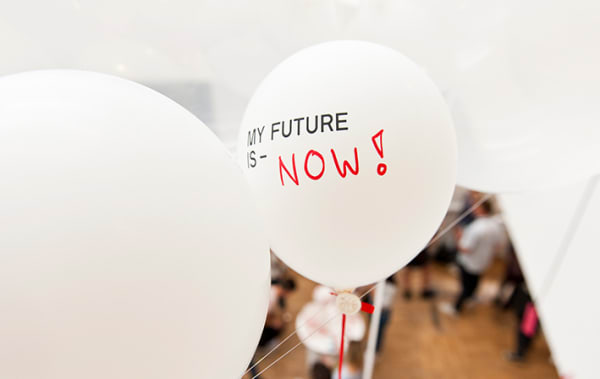 A white balloon floats with the text, my future is now, written on it.