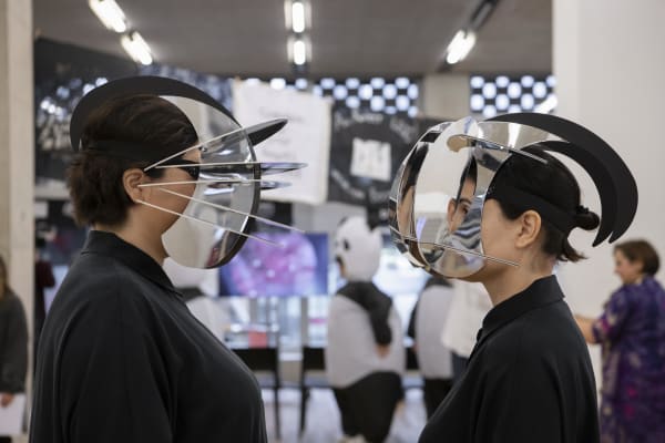 Two people facing each other wearing metal headpieces