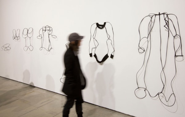 A person walking past wire sculptures on display in the Lethaby Gallery