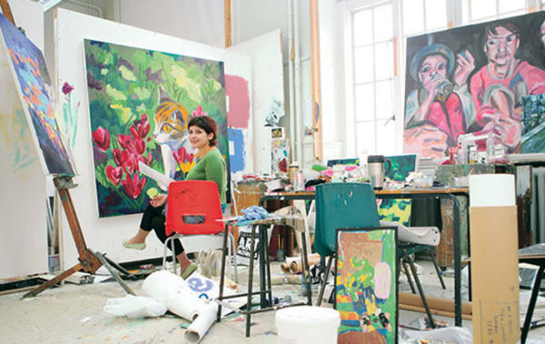 A painter in her studio looking to camera