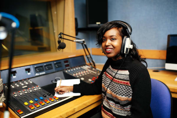 A journalism student at London College of Fashion wearing earphones in a broadcasting studio