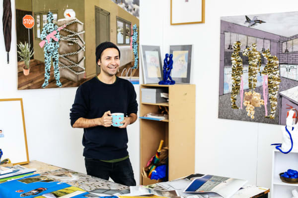 Mustafa Boga holding a cup surrounded by his collages