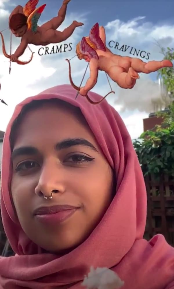 Smiling woman in a salmon coloured headscarf against a blue sky and clouds, with 2 illustrated cherubs above her head and the words 'Cramps' and 'Cravings'