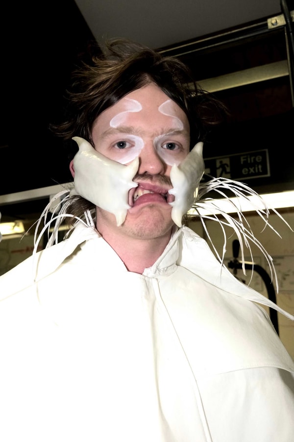 Portrait of person wearing mouth piece and white garment