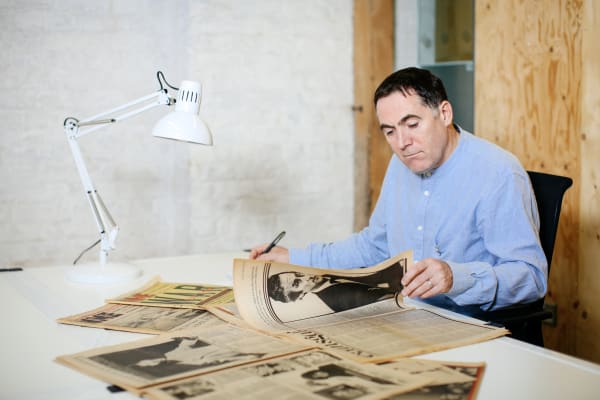 A man reading an old newspaper in a studio