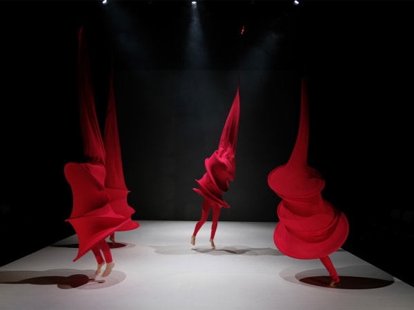 Four students dance on stage in red costumes