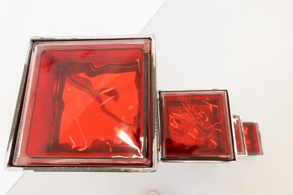 a sculpture of two red glass squares in different sizes. 