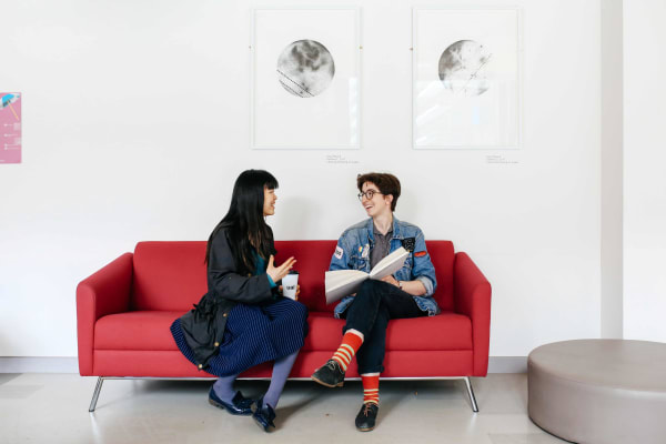 2 people sitting talking on a red sofa