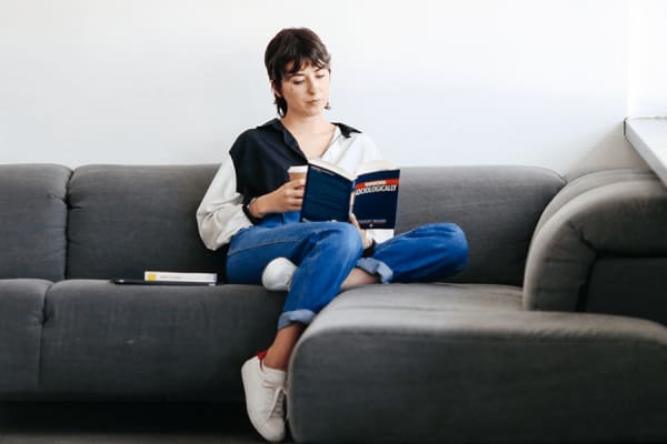 A woman sitting on a sofa reading a book