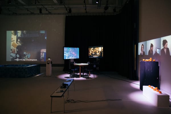 A dark performance lab with four lit screens each playing different material.