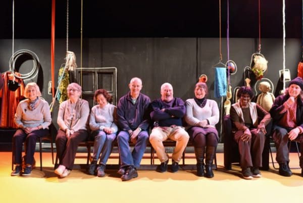 Elderly people sitting on chairs in a theatre workshop 