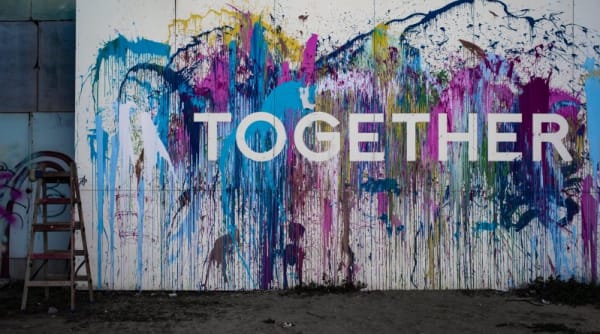 White wall covered in purple and blue paint with stencilled word 'together' visible