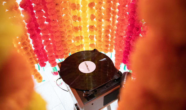 A record player sits inside a cylinder made from strings of flowers.
