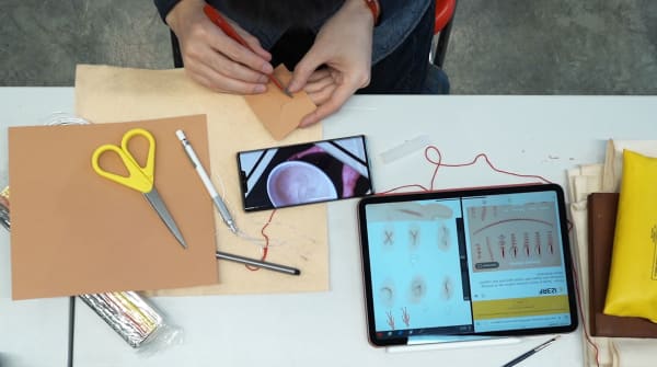 Close up of hands working on a design with a table with screens and materials
