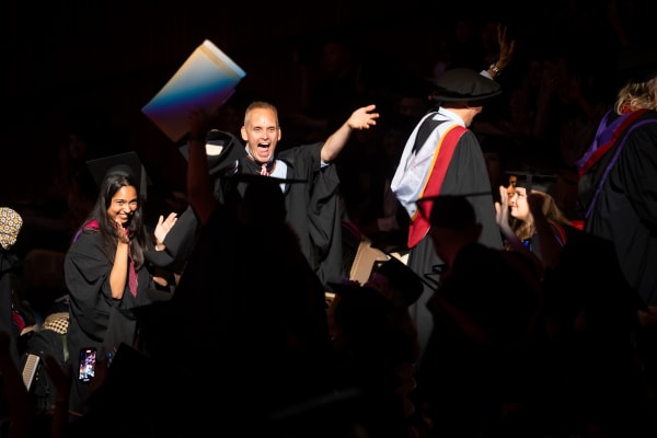 UAL member of staff cheering on the audience as they walk up the stairs