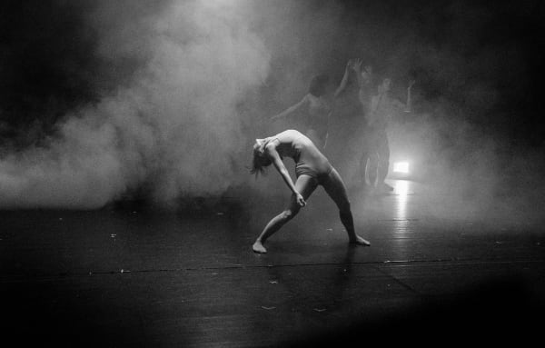 A performance artist on stage, surrounded by fog 