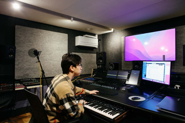 Student working in sound studios, with keyboard and large screen.