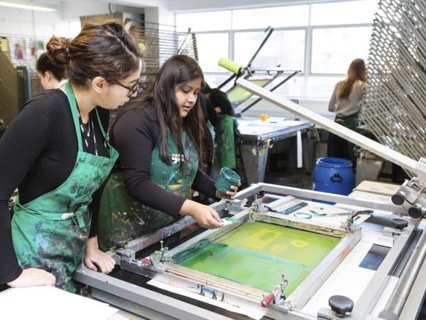 2 Students work together to make a screenprint in the print studio.