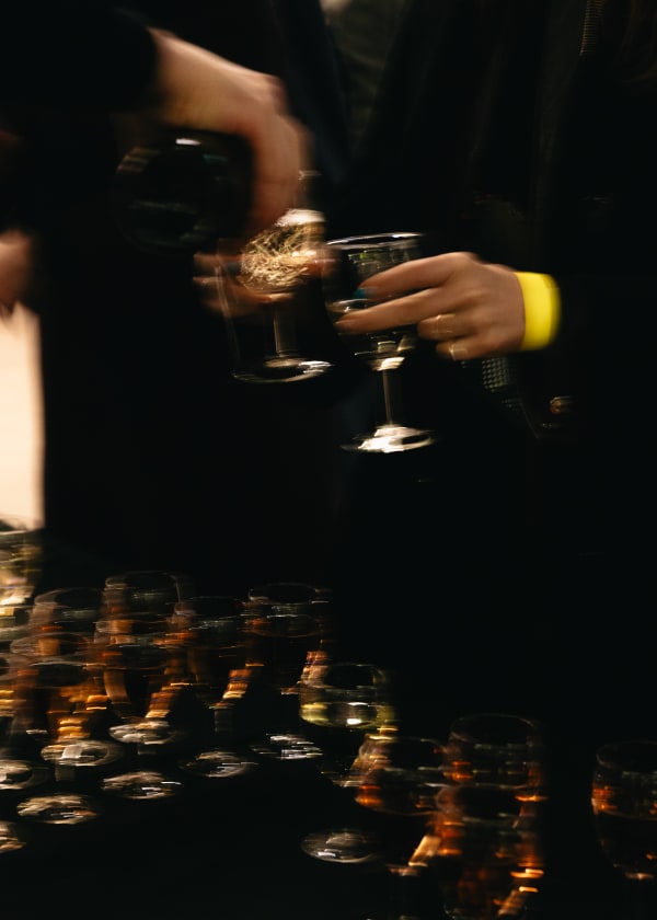 Picture of a hand holding a glass of white wine and a table full of empty glasses
