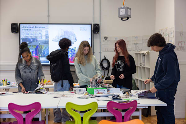 5 students looking through magazines on a classroom table