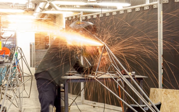 A student welding in the metal workshop