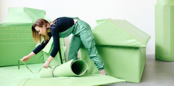 Female artist interacting with green sculptures 