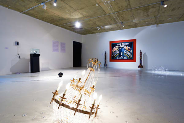 A curated collection in a gallery with a shattered but lit chandelier on the floor.