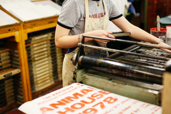 Student in apron working on the letterpress 