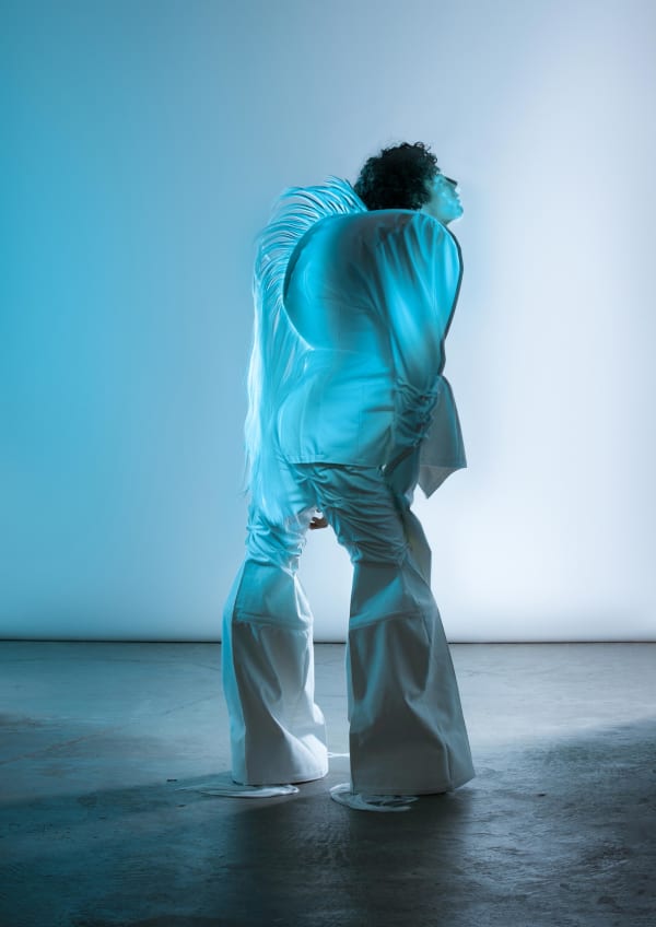 Figure wearing white garments lit in blue