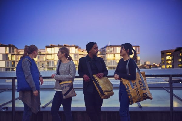 Four people chatting with large yellow bags