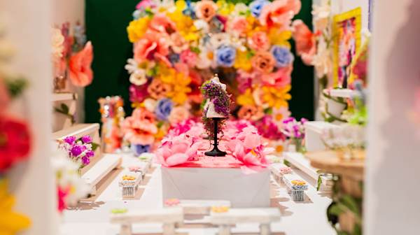 Mini sculpture of a fashion show catwalk surrounded by colourful flowers