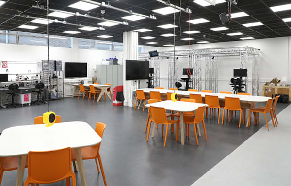 empty workshop space with chairs, tables, tv screen's vr booths and coding area