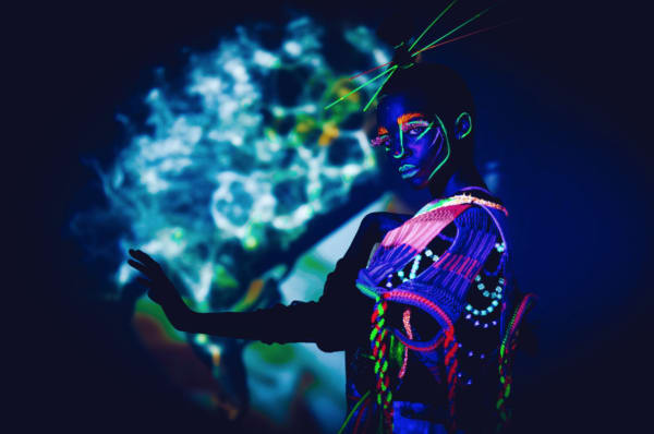Girl in the dark in a glowing neon dress and makeup 
